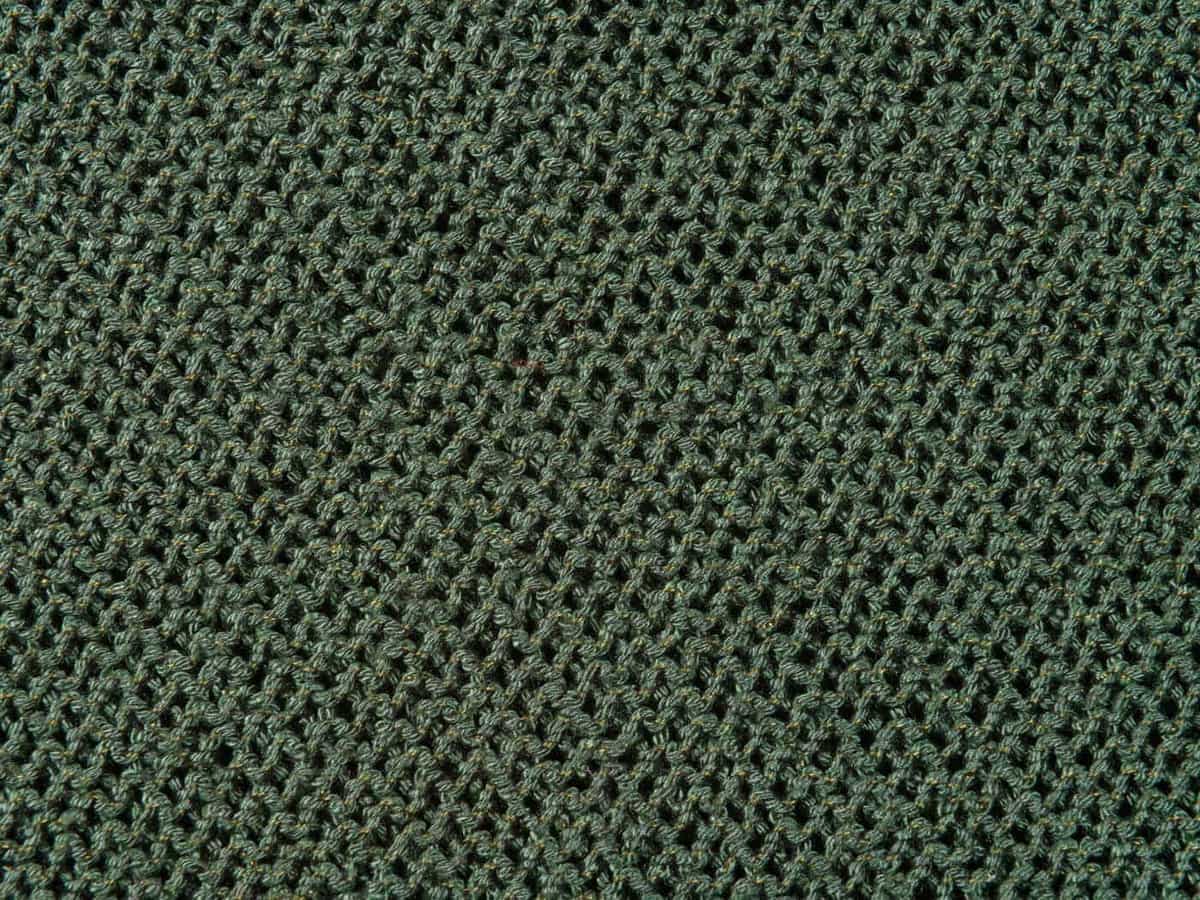 Detailed view of a green knitted fabric showing its texture and pattern