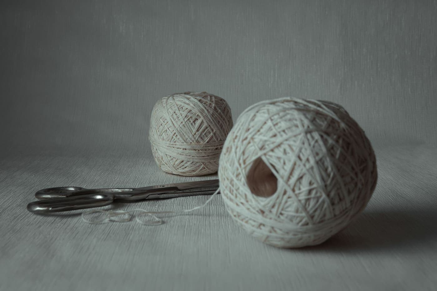 Close-up of yarn balls and scissors on a plain surface