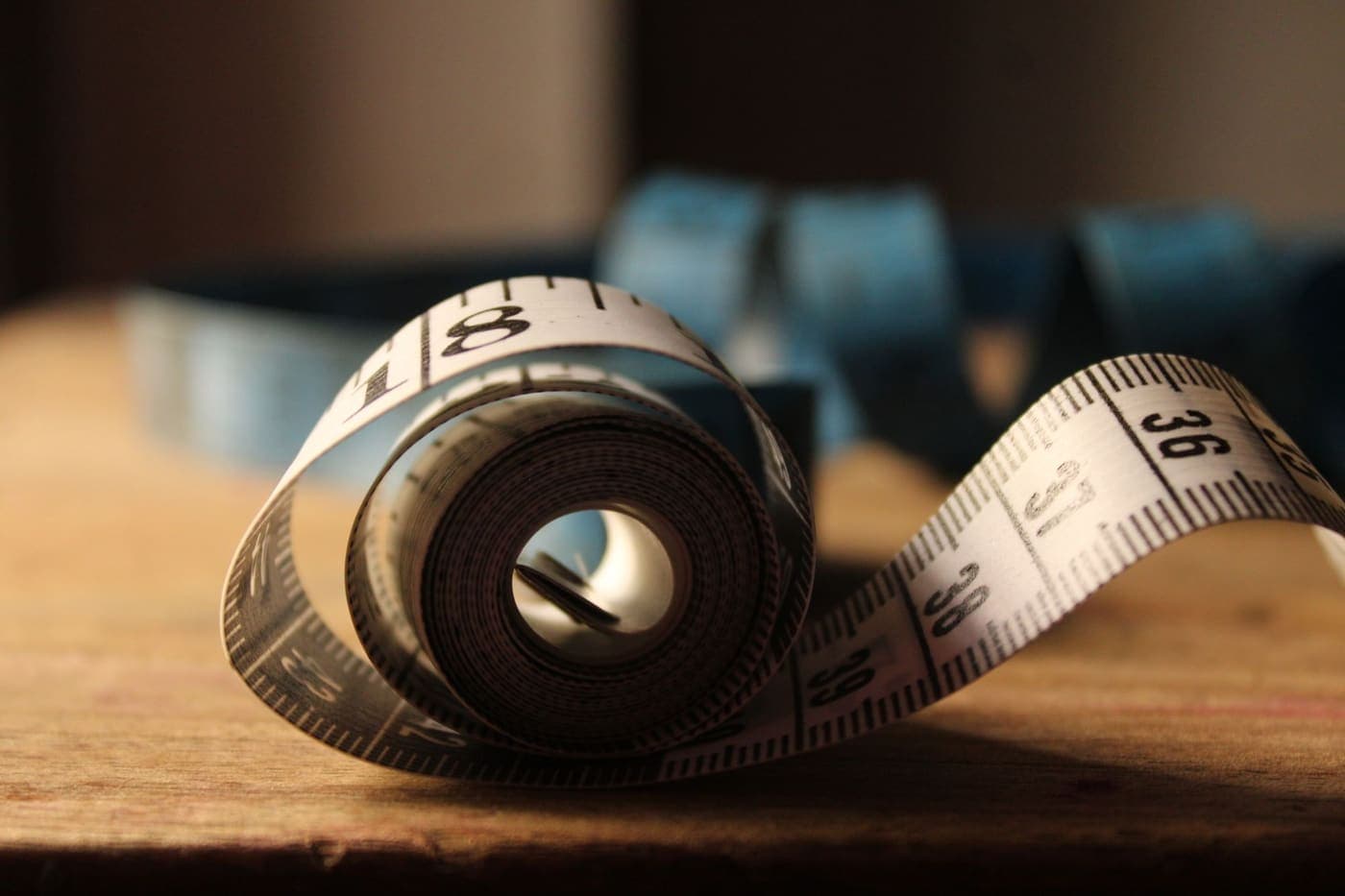 A rolled measuring tape showing its numbers on a wooden table