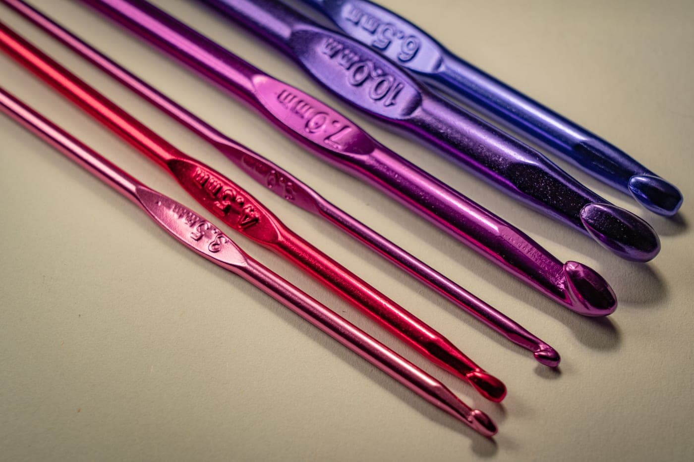 Crochet hooks of several sizes fanned out on a plain background