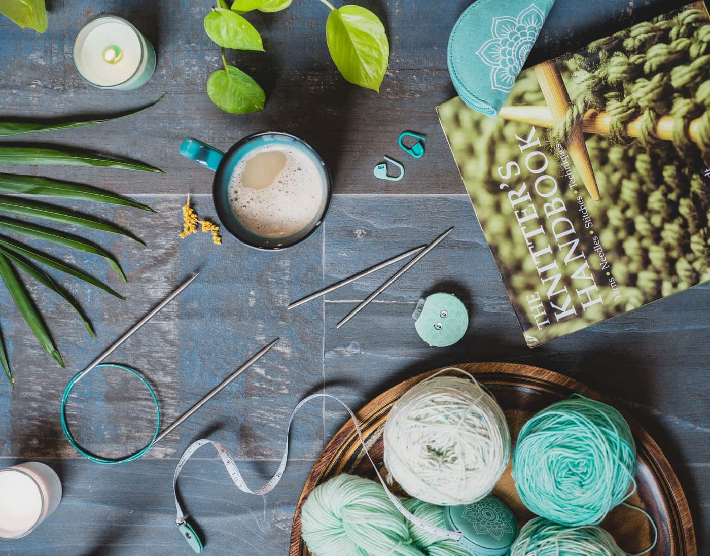 A flat lay of knitting tools, yarn and coffee