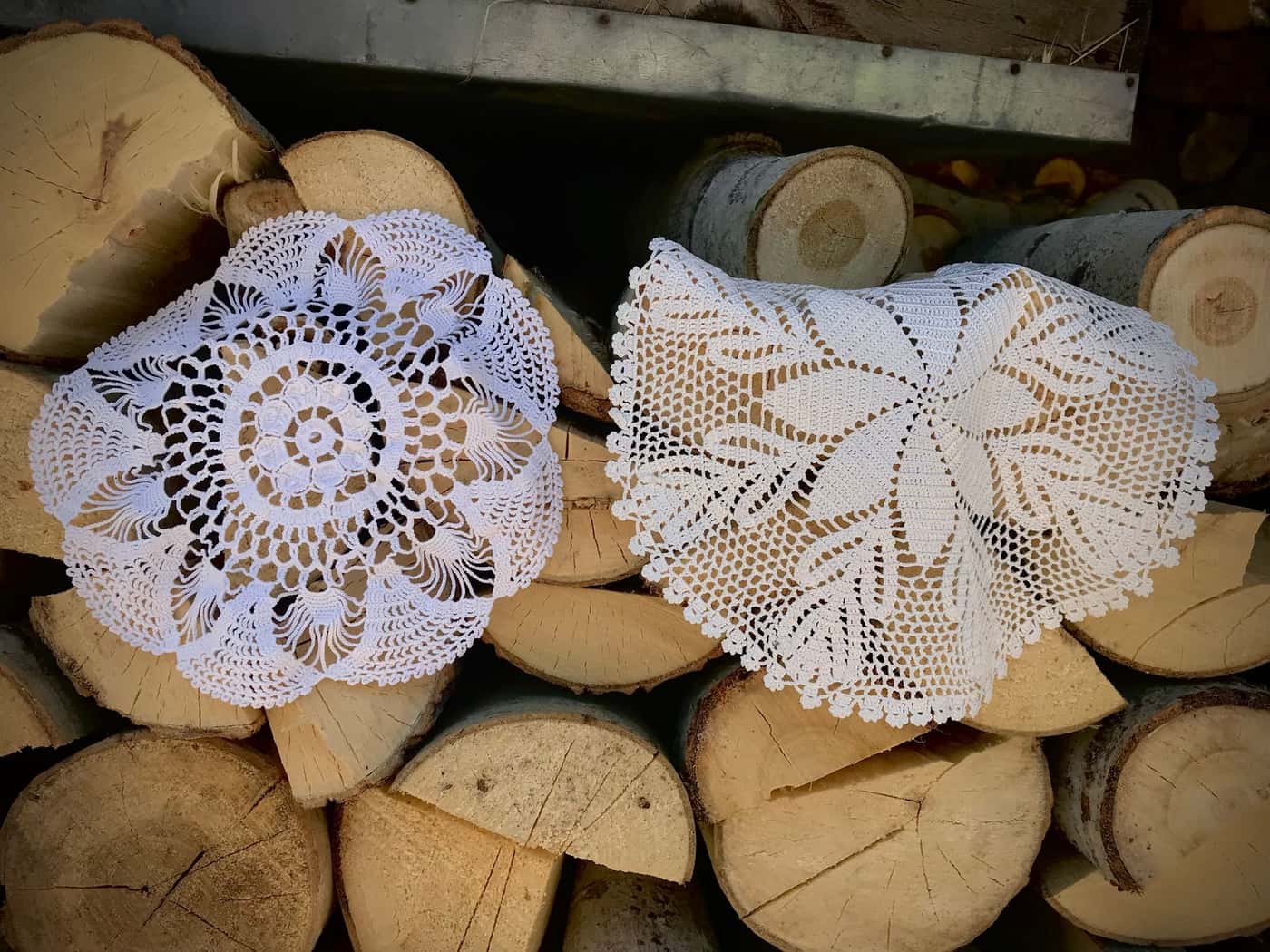 Crochet doilies displayed on a stack of firewood