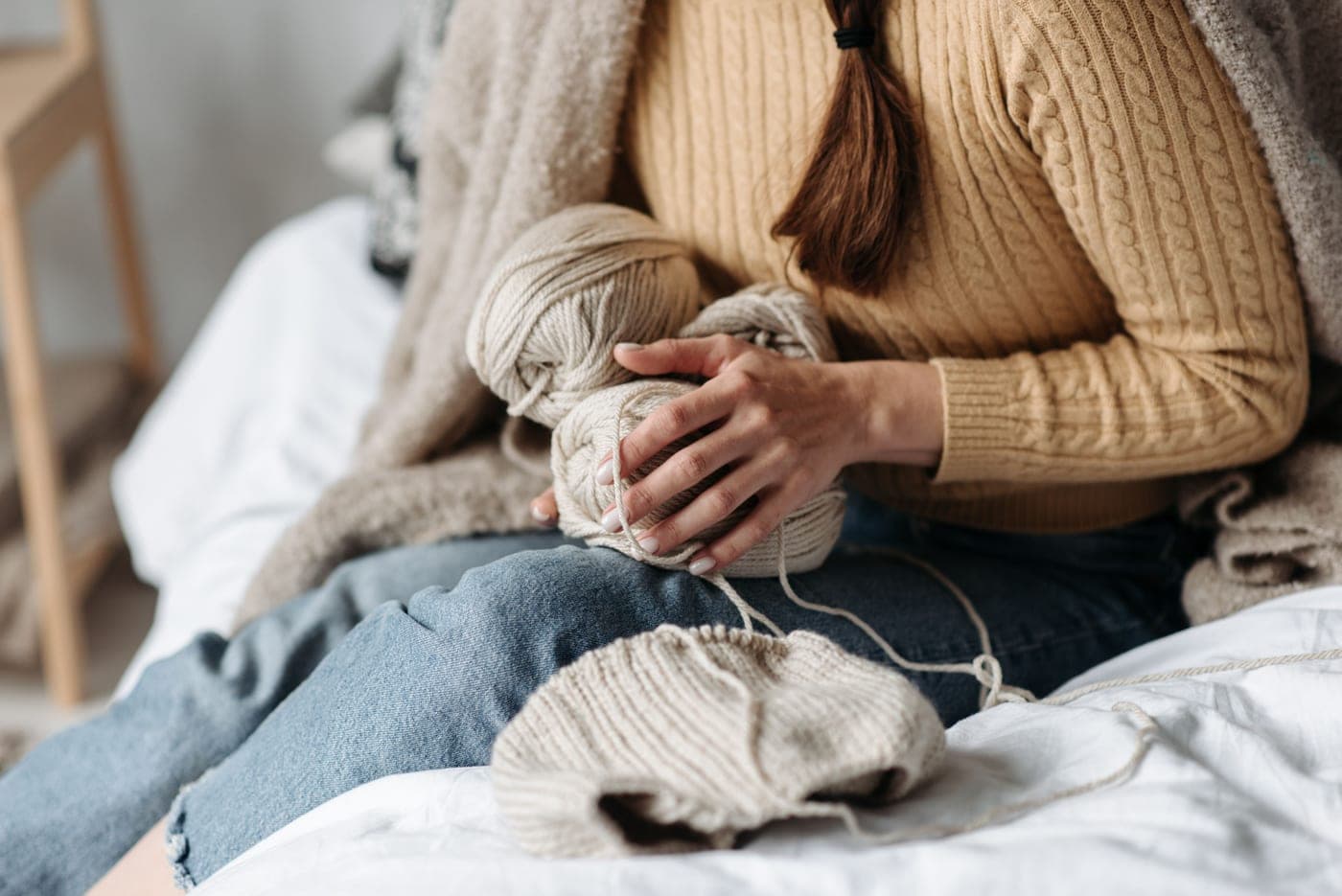 A large knitted blanket in progress draped over a chair with yarn beside it