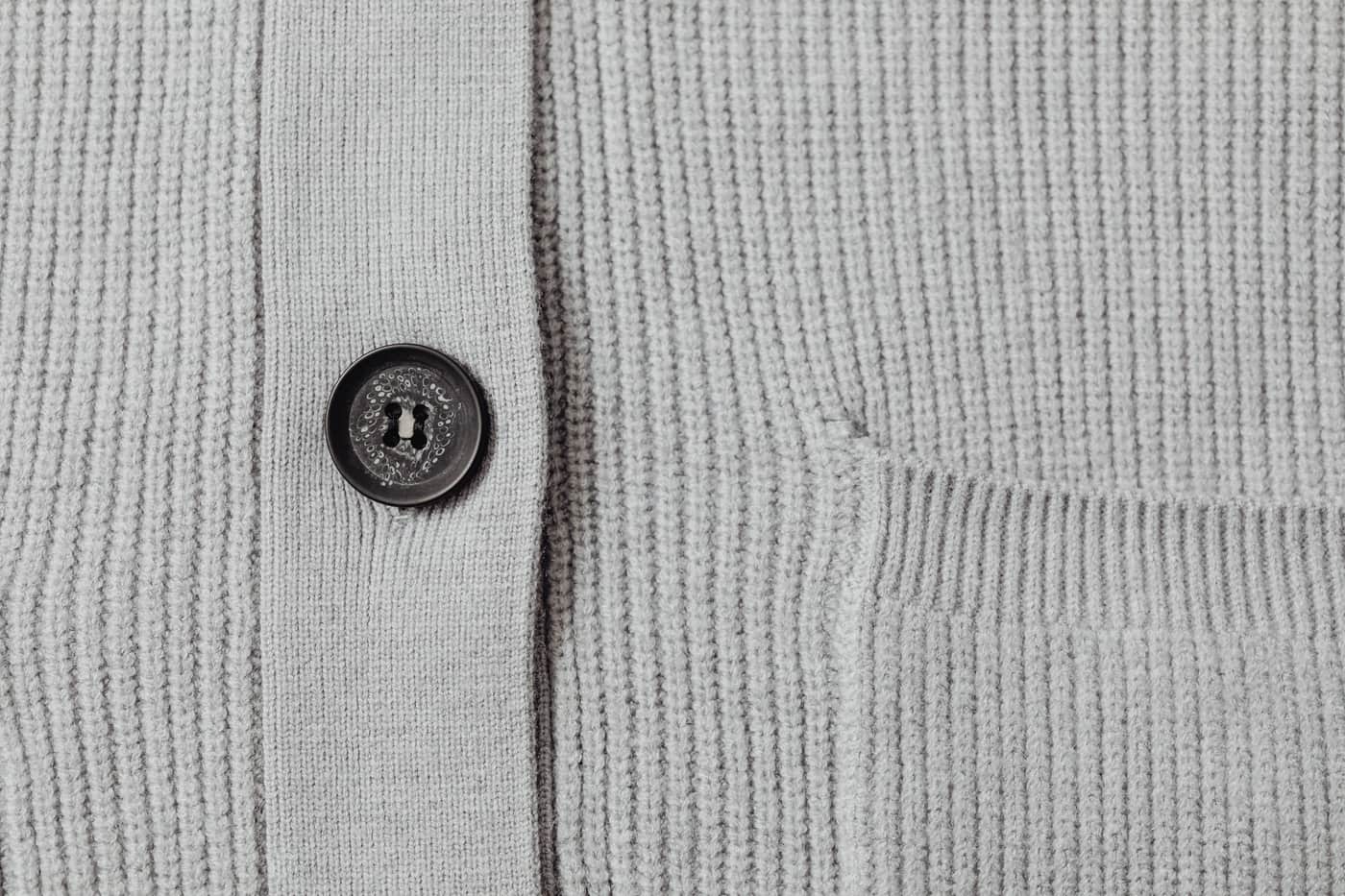 A cardigan front panel in progress with a button band and yarn beside it