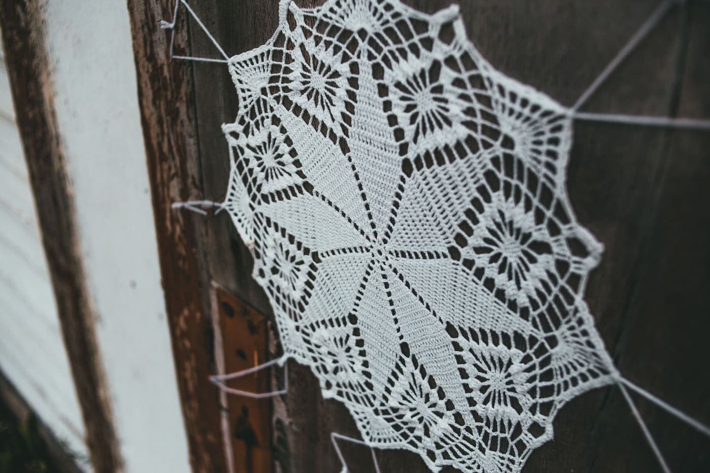 A handmade lace decoration hanging on a rustic wooden door
