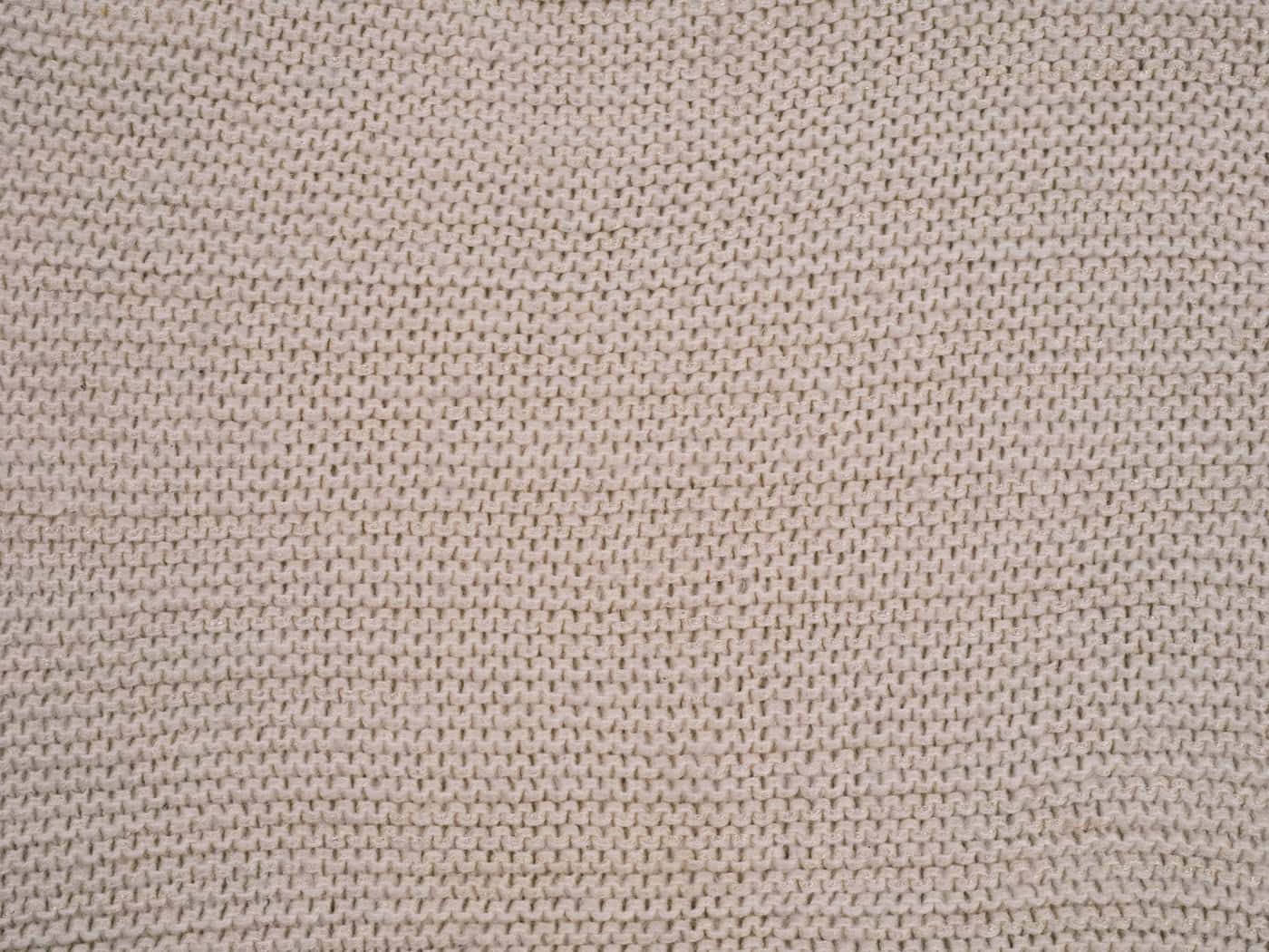 Close-up of a beige knitted textile with a textured weaving pattern