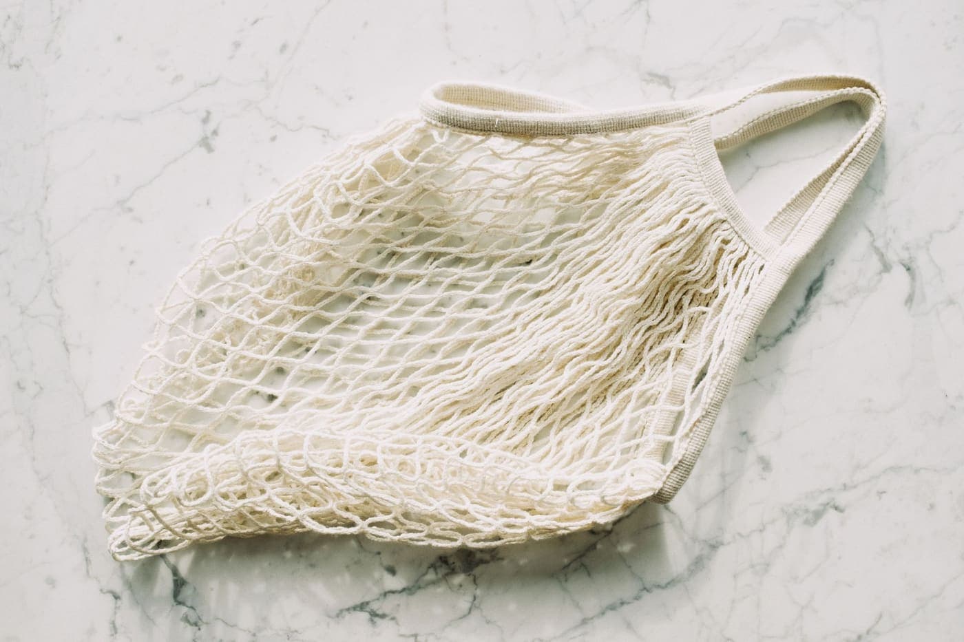 A simple white mesh bag laid flat on a marble surface