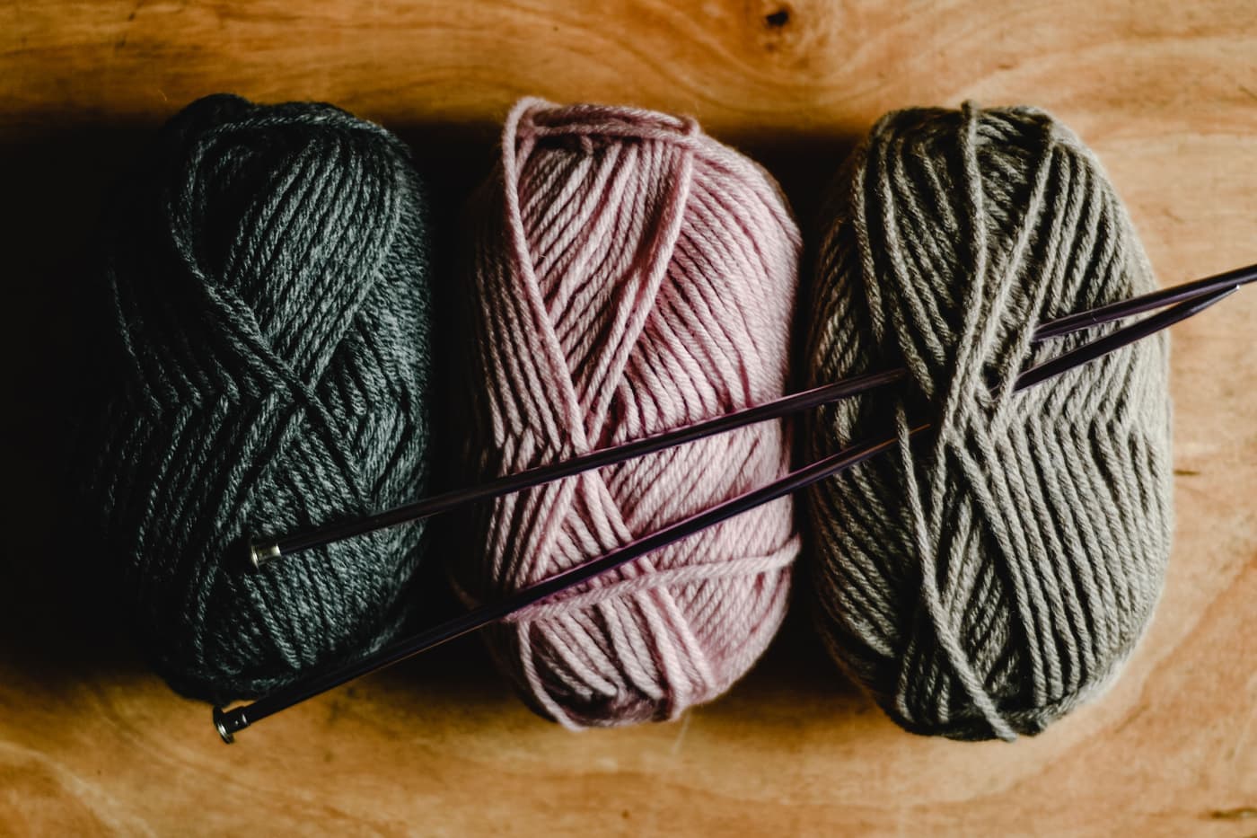 Skeins of fine merino wool yarn in natural shades on a plain surface