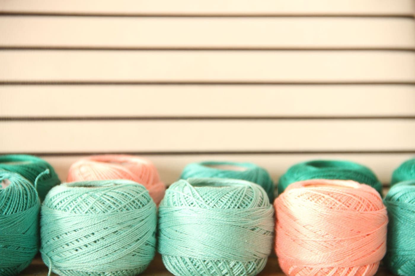 Pastel yarn balls arranged against a striped backdrop