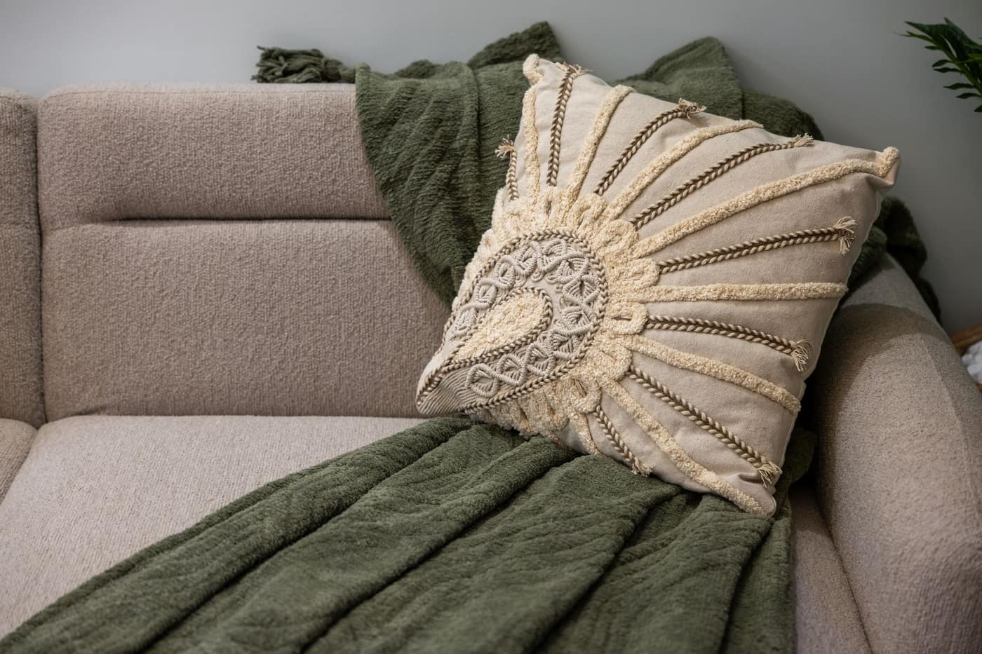 A bohemian styled couch with a textured cushion and a throw