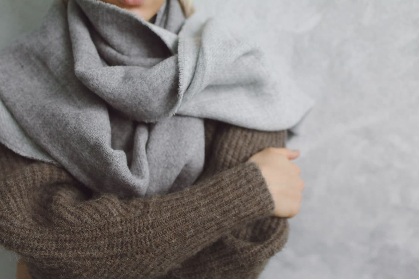 A person wearing a knitted sweater and scarf