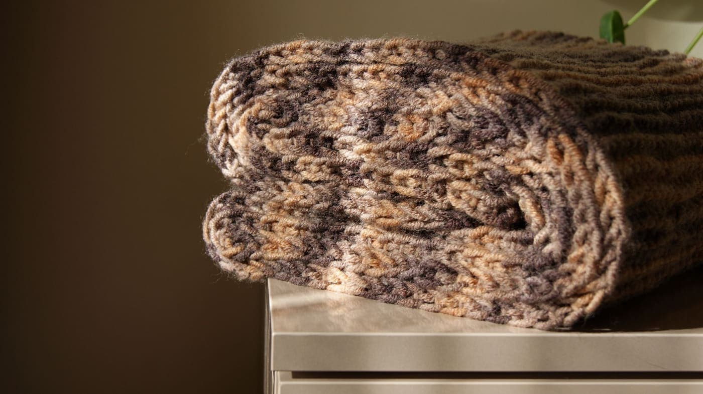 A soft knitted scarf in warm colors folded neatly on a tabletop in natural light