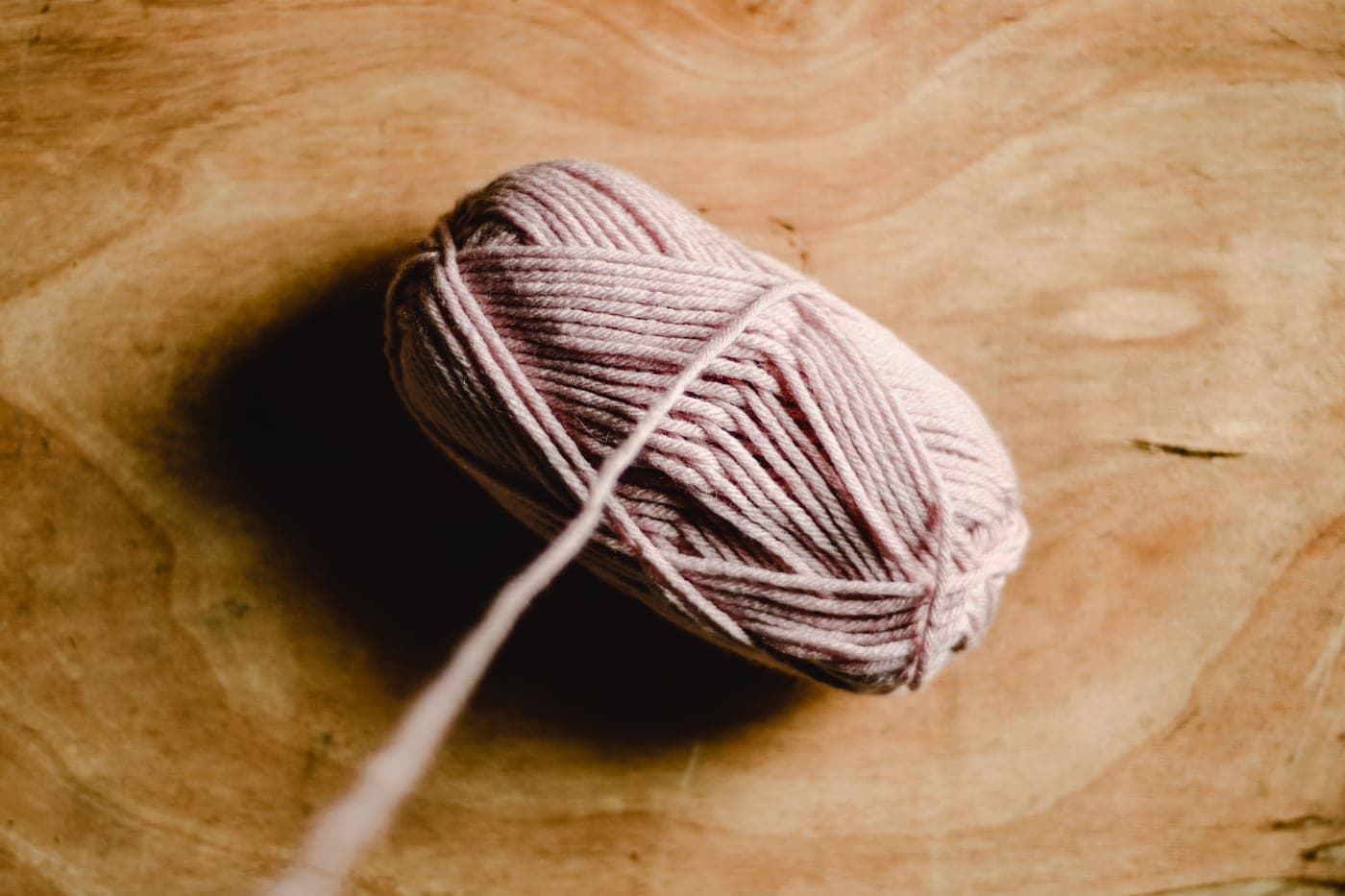 A ball of acrylic yarn beside a skein of wool on a plain work surface